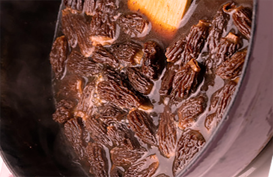 morels in a red wine sauce cooking in a deep frying pan