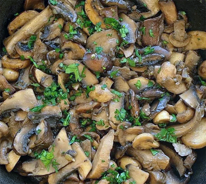 mixed mushrooms fried with parsley and garlic in a frying pan