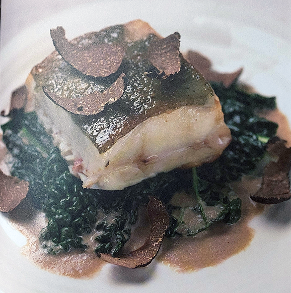 pan-fried turbot square served on a bed of savoy cabbage and topped with a summer truffle shaving sauce