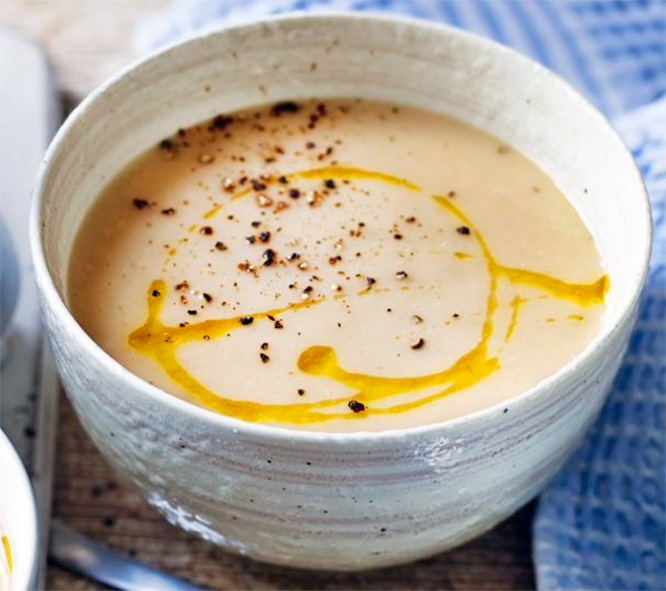 parsnip and apple soup served in a bowl with a garnish of cracked pepper and oil