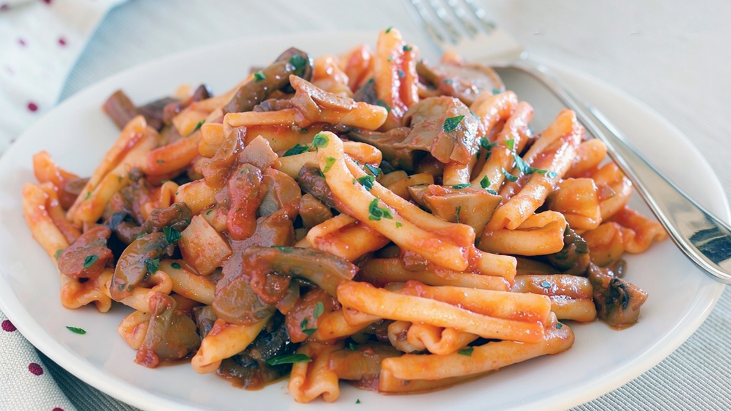 casarecce pasta tossed with mixed mushroom sauce and served on a white plate