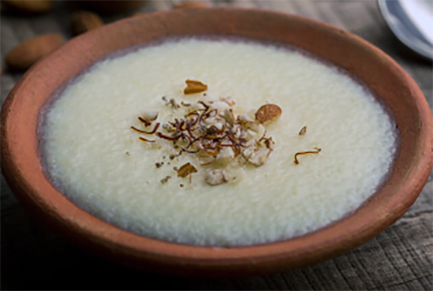 phirni served in an earthenware bowl with a nut saffron thread garnish