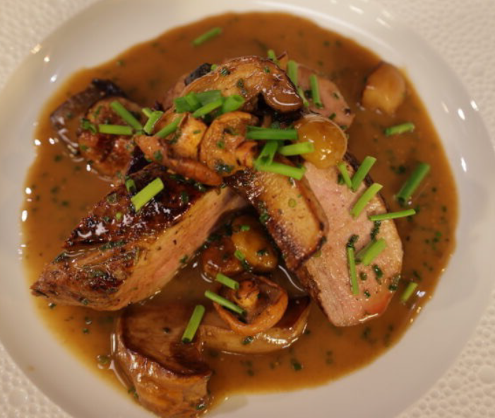 Pork tenderloin slices with mushrooms in a sauce garnished with snipped chives