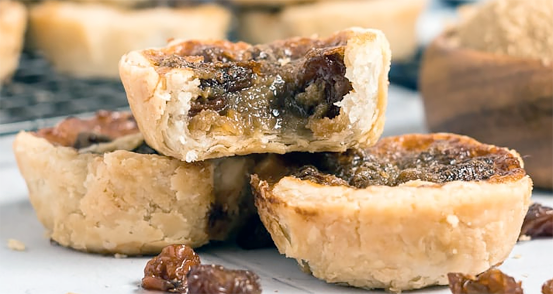 tree raisin butter tarts piled into a pyramid with a bite taken from the top one