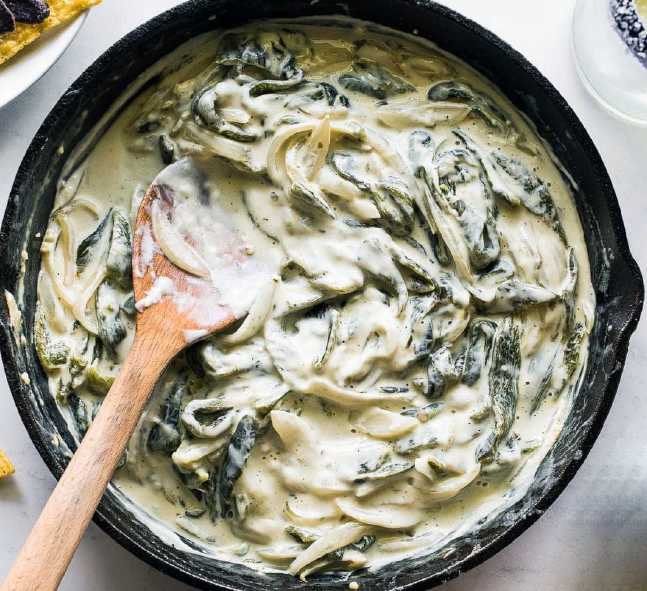 rajas con crema in a frying pan with a wooden spoon
