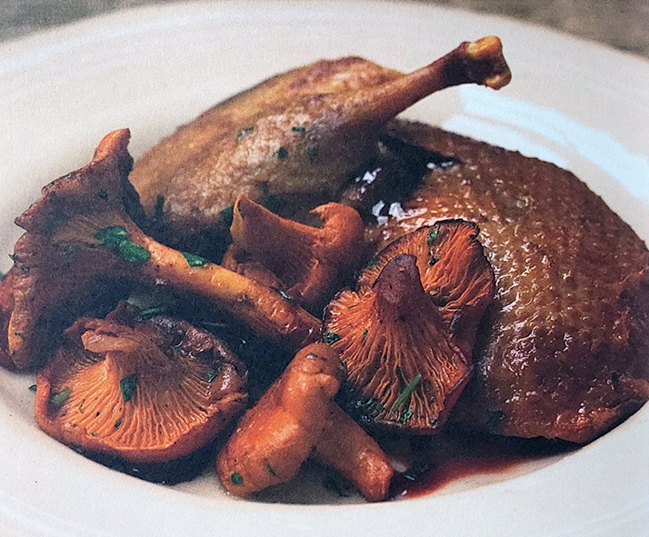 half a roast wild mallard on a plate with chanterelles all drizzled with sauce
