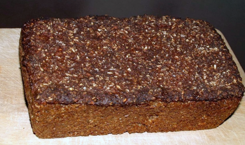 Loaf of Rugbrød, Danish rye bread on a wooden chopping board