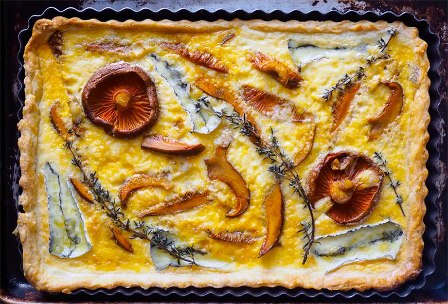 tart of saffron milk cap mushrooms, brie and thyme in an egg base in a pastry case on a baking tray
