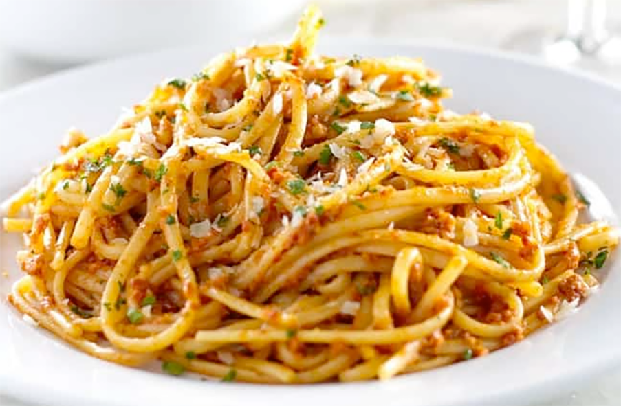spaghetti tossed with sun-dried tomato and garlic pesto piled in a white pasta bowl