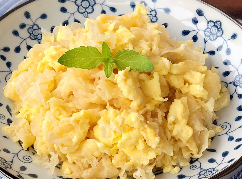 stir-fried scrambled eggs on a plate garnished with a sprig of mint