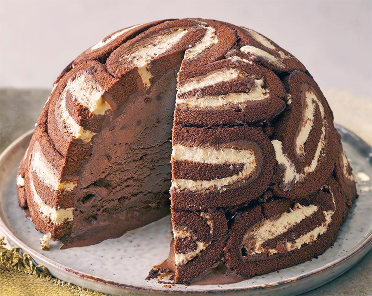 swiss roll frozen cake turned out onto a plate with a wedge removed to reveal the ice cream centre