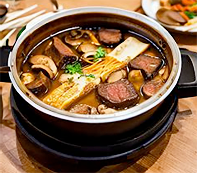 Boiling pot of hot pot stock in the centre of a table