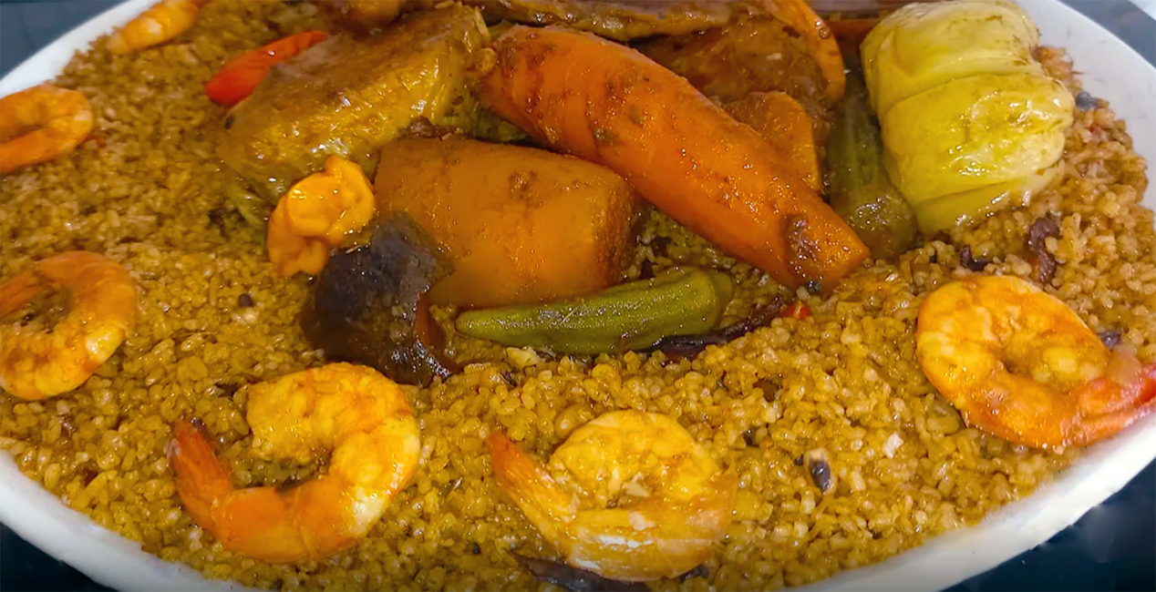 mixed vegetables and dried fish served on a bed of couscous surrounded by a ring of king prawns