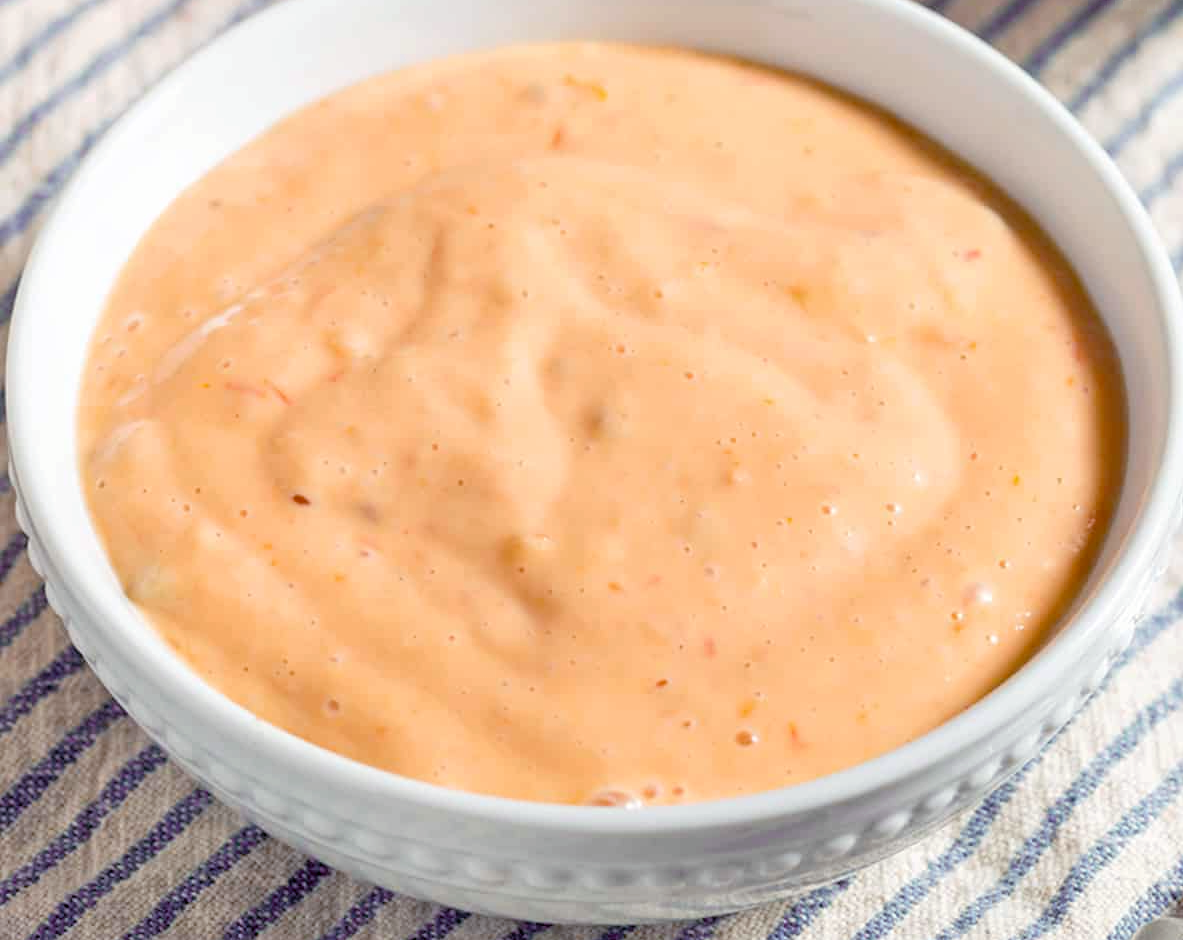 thousand island dressing in a white bowl on a striped tablecloth