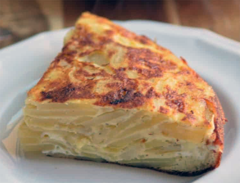 wedge of Spanish tortilla de patatas on a white plate showing the potato filling