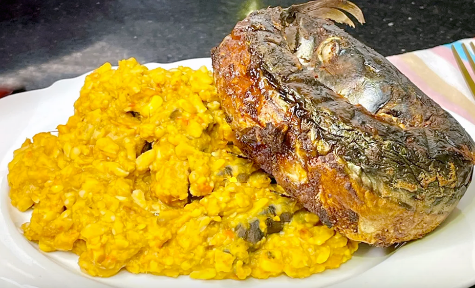 yellow breadfruit porridge served topped with a fried fish shaped in a ring