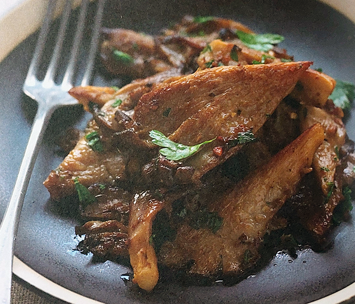 warm salad of oyster mushrooms served on a plate with a fork
