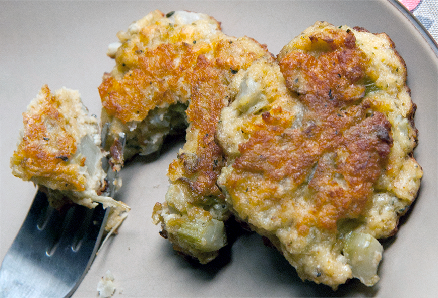 two wild food stalk fritters on a plate, one cut with a fork