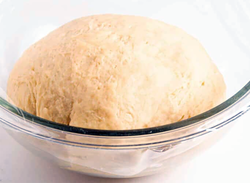 yeasted empanada dough in a glass bowl