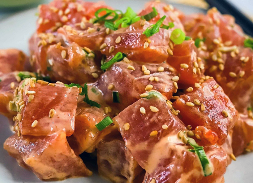 ahi poke garnished with spring onion and sesame seed served on a plate