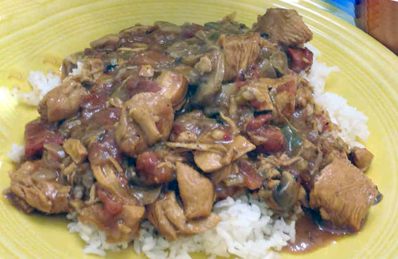 alligator in piquante sauce served over rice on a yellow plate
