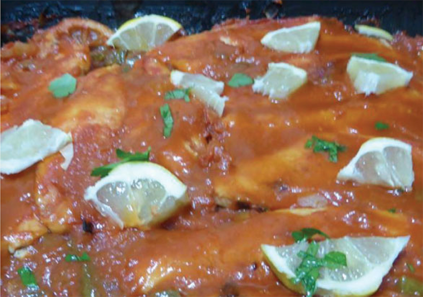 haddock fillets baked in tomato sauce with lemons served in a dish with sliced lemon garnish