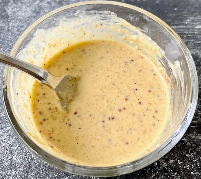 <dsc><em>Bayou Smoky Creole Mustard Sauce</em> is a traditional American recipe (from Louisiana) for a classic dish of sausage and okra fried with white yellow creole mustard sauce in a small glass bowl with a spoon