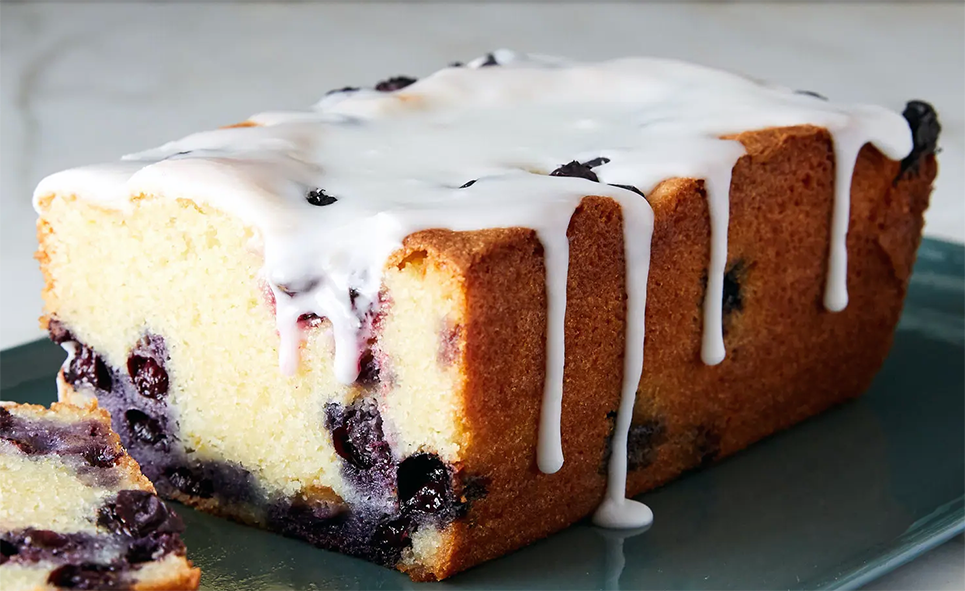 Bilberry and almond snacking cake baked as a loaf cake with a slice removed