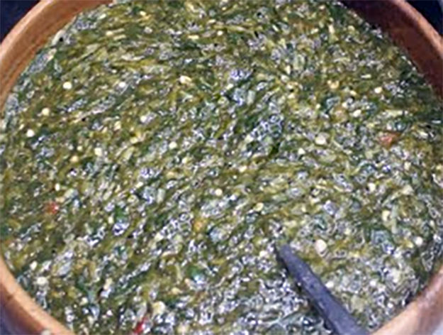 green bissap (hibiscus) beguedji sauce served in an earthenware bowl