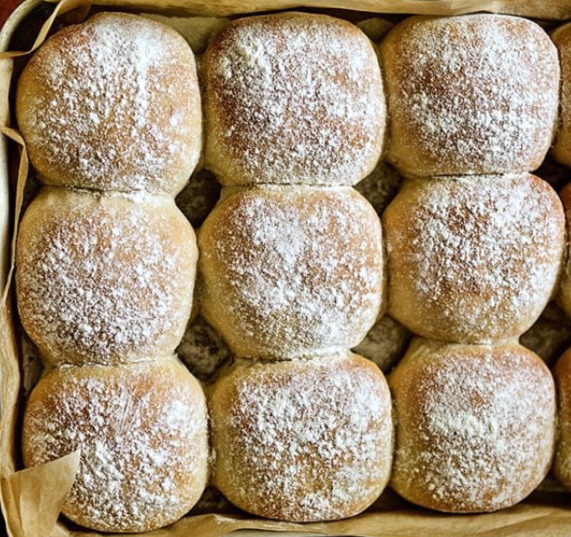 nine baked floured Irish blaas bread rolls in a square baking dish lined with baking parchment