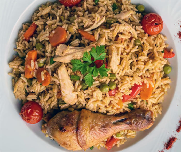 Bosnian chicken and rice pilaf served on a plate with a chicken thigh