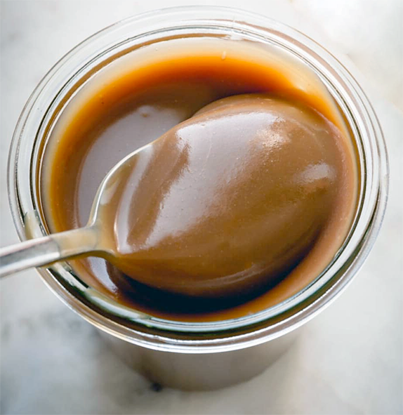 butterscotch rum sauce presented in a glass dariole with a spoon