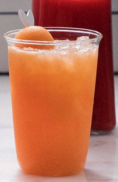 cantaloupe agua fresca served over ice in a glass garnished with a cantaloupe melon ball