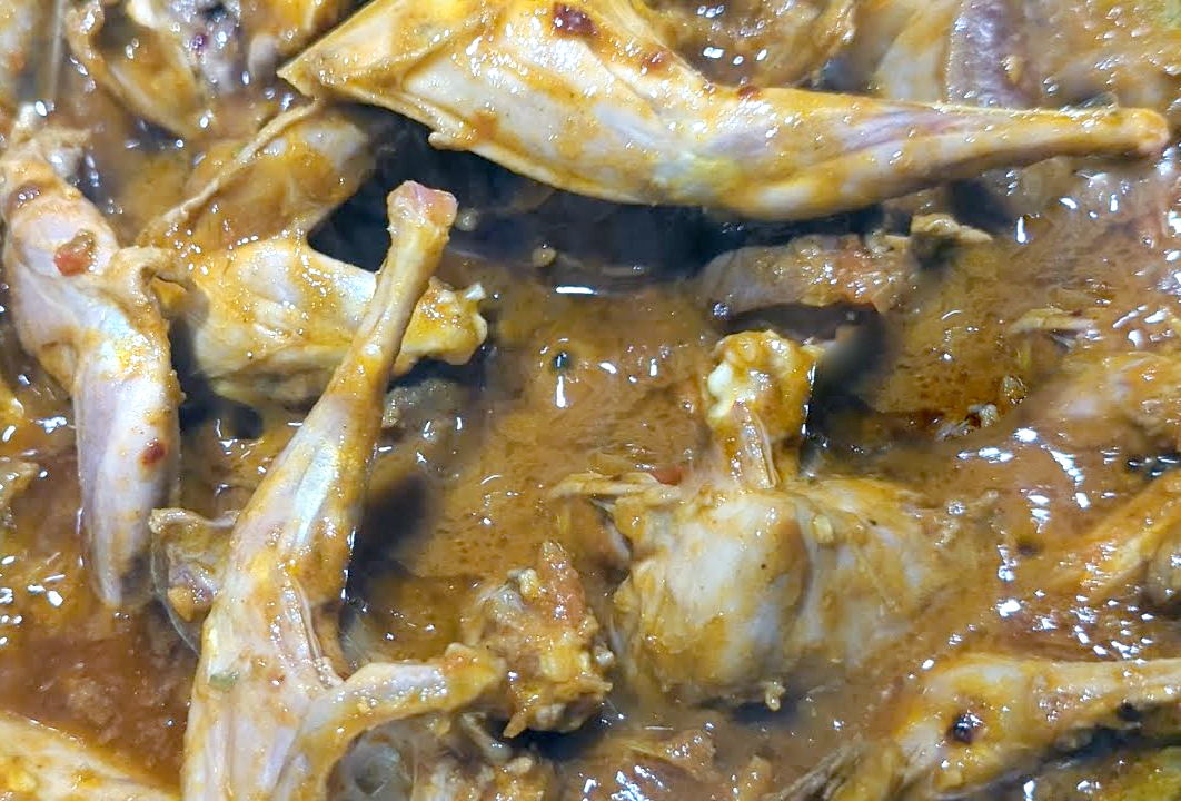 Stew of pigeon pieces in coconut milk in a wok