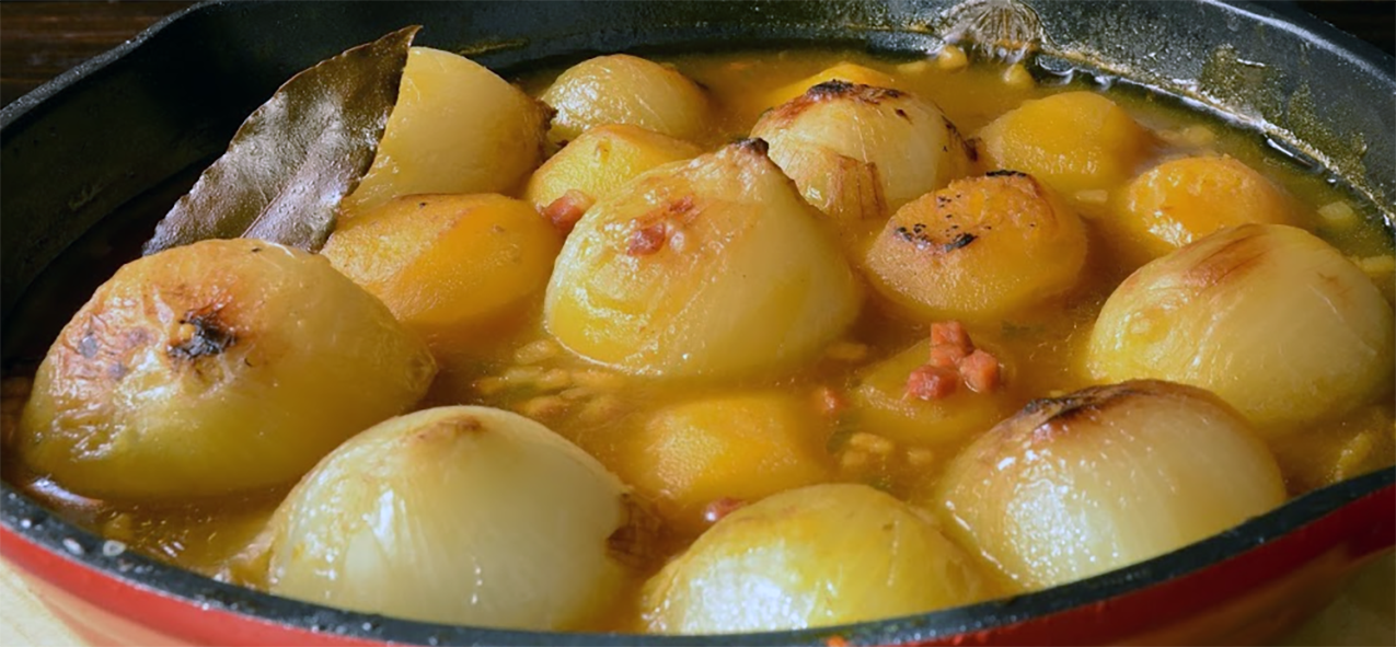 braised spanish baby onions in a frying pan with a bay leaf