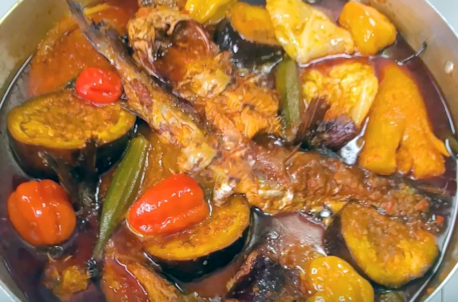 smoked catfish with vegetables and chillies in a red oil base in a serving dish