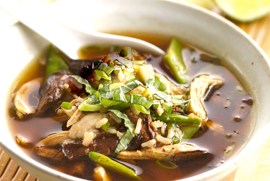 Chinese chicken and mushroom soup garnished with spring onions and ginger served in a bowl