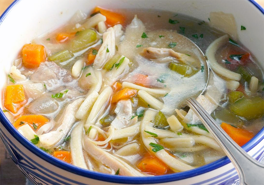 chicken noodle soup with beansprouts and carrots served in a bowl with a spoon