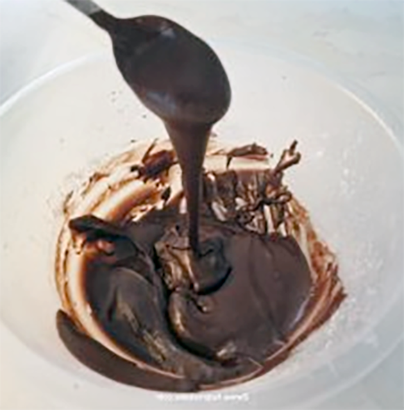 chocolate glacé icing drizzled from a spoon into a plastic bowl