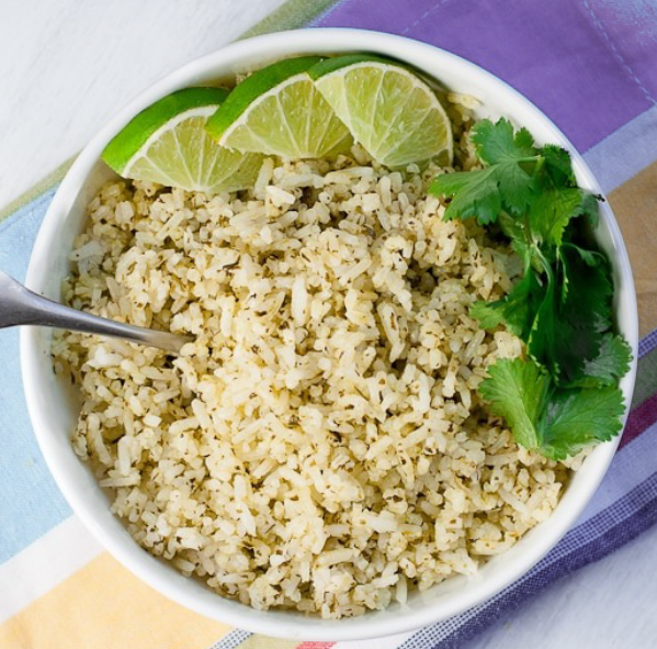 coriander lime rice in a bowl with a garnish of coriander leaves and lime wedges
