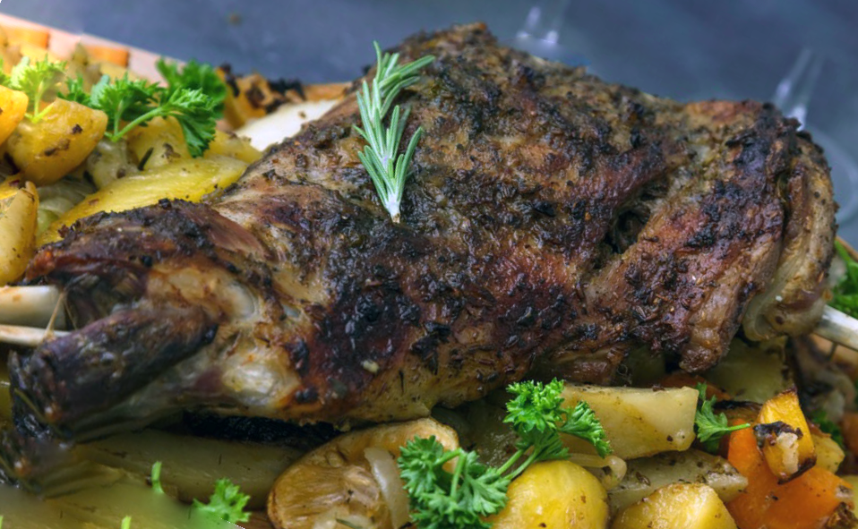 Coleraine roast lamb leg garnished with a sprig of rosemary on a bed of roasted potatoes