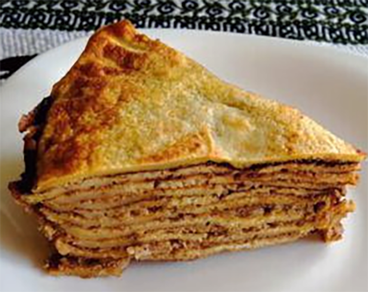 wedge of stacked baked pancakes with chocolate filling on a plate