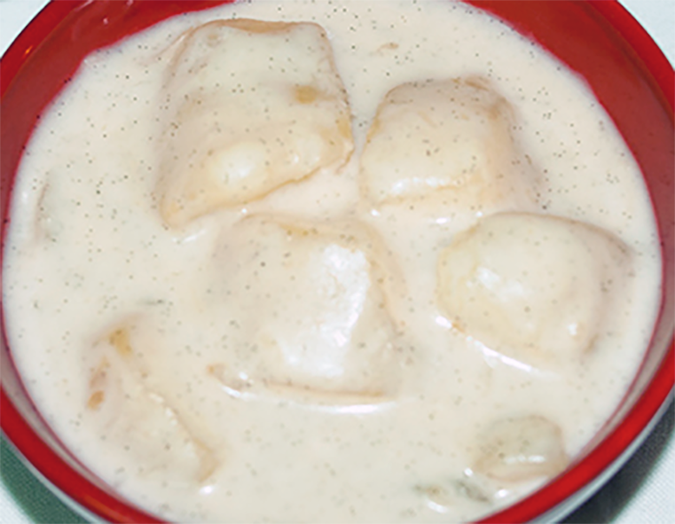 stewed cassava pieces served in a bowl with coconut milk