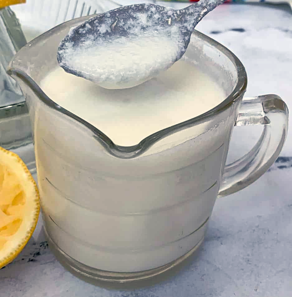 sweet buttermilk made from sweetened milk and lemon juice in a jug with some lifted on a spoon