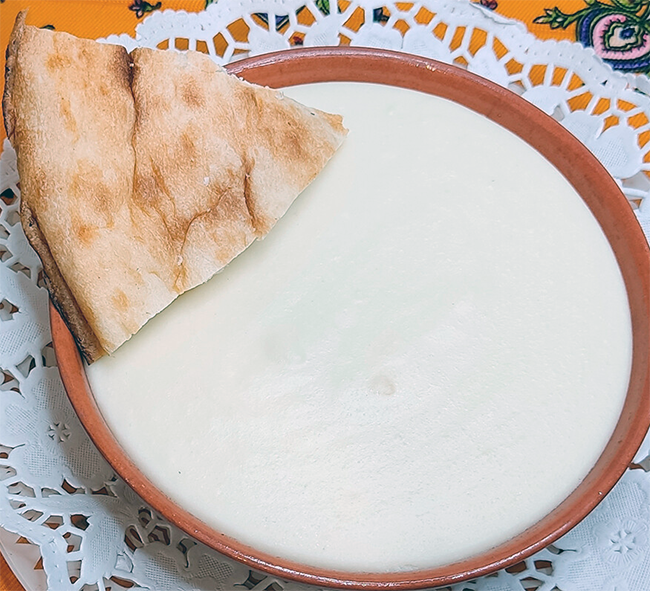 Dzykka cheese porridge served in a bowl with a piece of flatbread