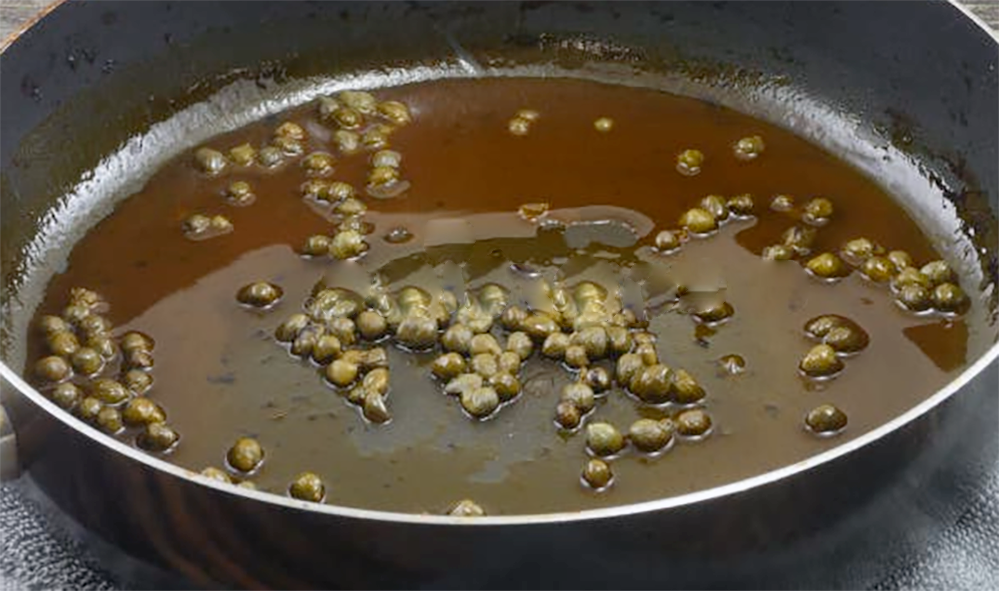 brown caper sauce being prepared in a deep frying pan