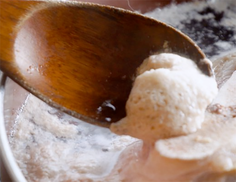 clarifying paste on a wooden spoon being added to a stock