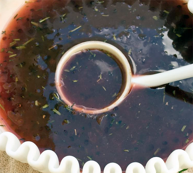 red wine and redcurrant sauce in a white bowl with a ladle