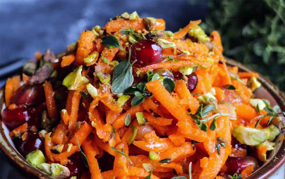grated carrot salad with pomegranates and bergamot served piled in a bowl