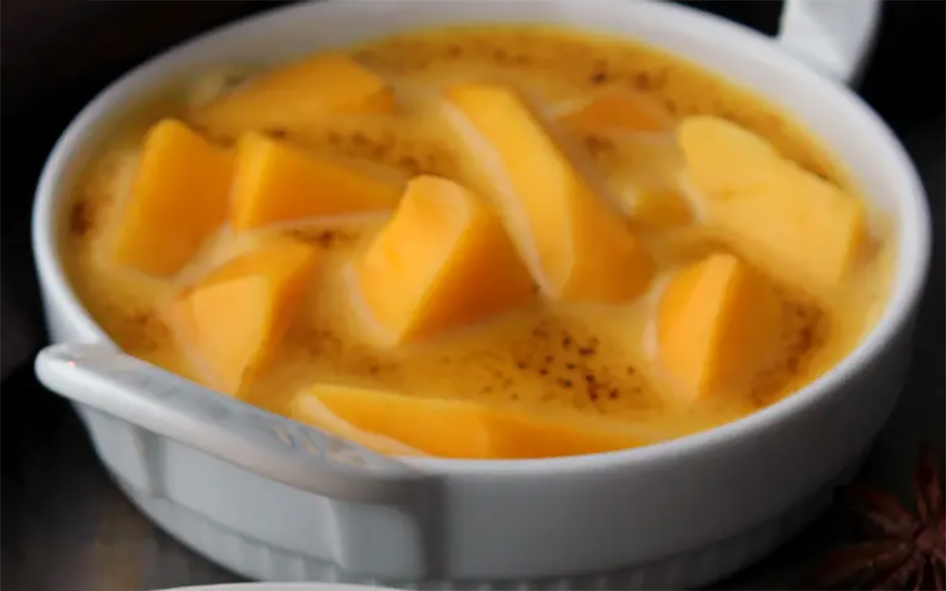 Gratin a la mangue dessert of mango chunks baked in a custard served in a bowl and garnished with ground cinnamon